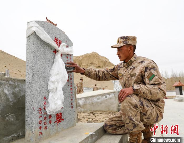图为阿里军分区某边防团官兵为革命先烈擦拭墓碑。　刘晓东 摄