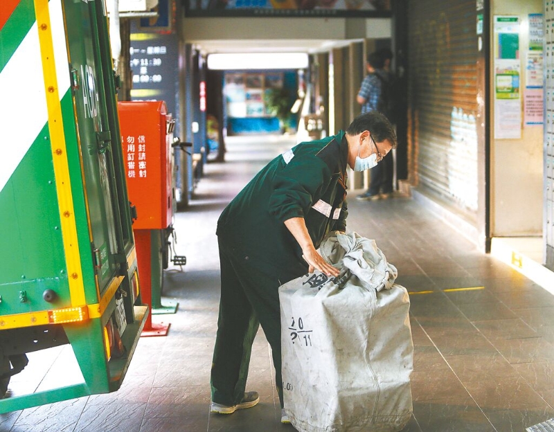 台湾基本工资明年拟调涨至新台币2万8000元，学者示警恐推升物价。图为邮务士装载邮件包裹。（图源：台湾《中国时报》）