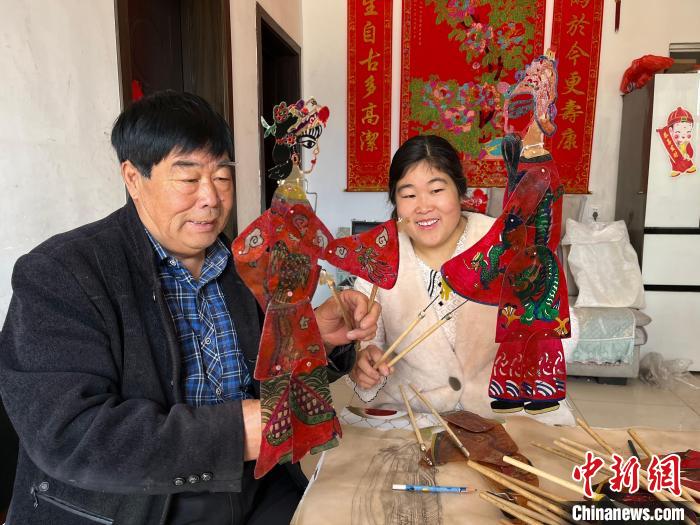 圖為馮克獻和女兒展示製作完成的皮影道具。　馬瑾 攝