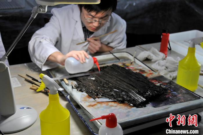 “天回醫簡”出土不久，文保工作者正在進行其表面清理工作。　成都文物考古研究院供圖