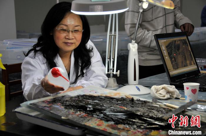 “天回醫簡”出土不久，肖嶙正在進行其表面清理工作。　成都文物考古研究院供圖