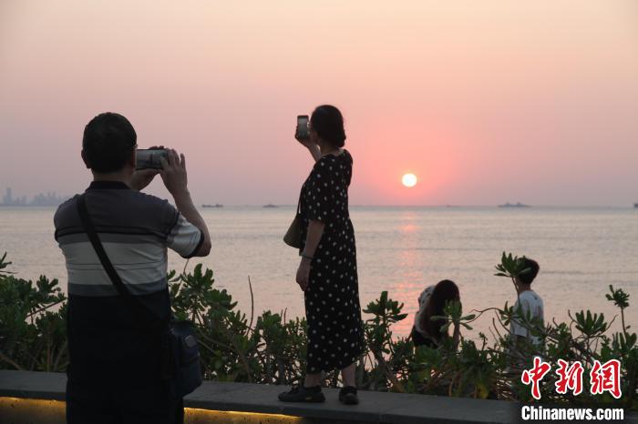 “立夏”时节，海口市民游客傍晚出游欣赏落日，拍照留念。　张月和 摄