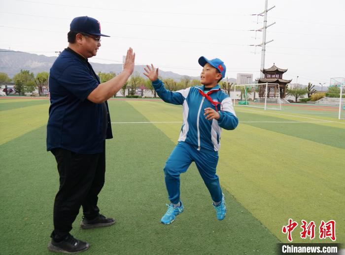 图为台湾棒球教练刘兴鸿和小棒球手互相击掌鼓励。　马铭言 摄