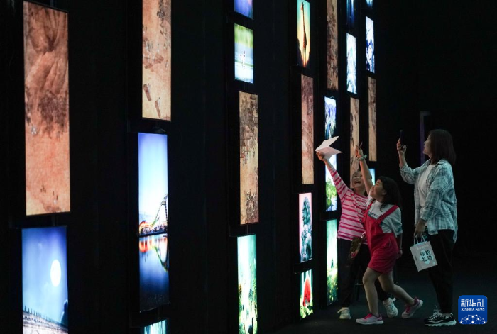在位于北京的瞭仓数字藏品博物馆，观众在一间以永定河生态为主题、展示动态画作、实景照片和人工智能生成画作的展厅里参观(5月14日摄)。
