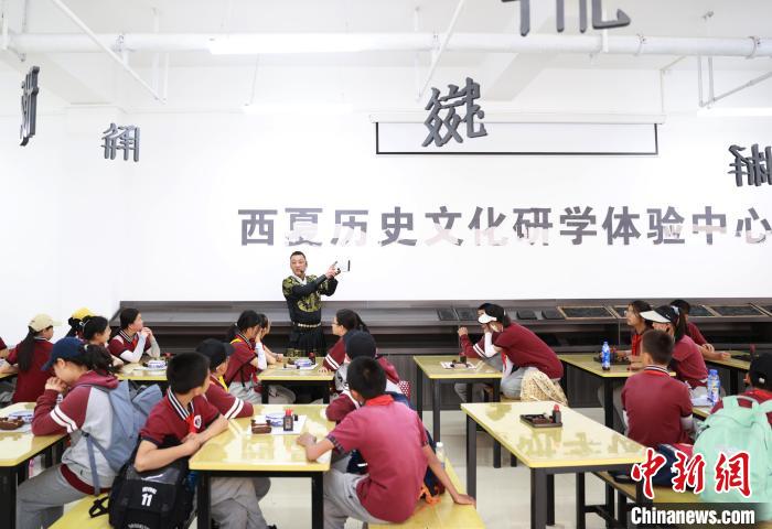银川景博学校的学生们在宁夏西夏王陵景区体验西夏文木活字印刷术。　于晶 摄