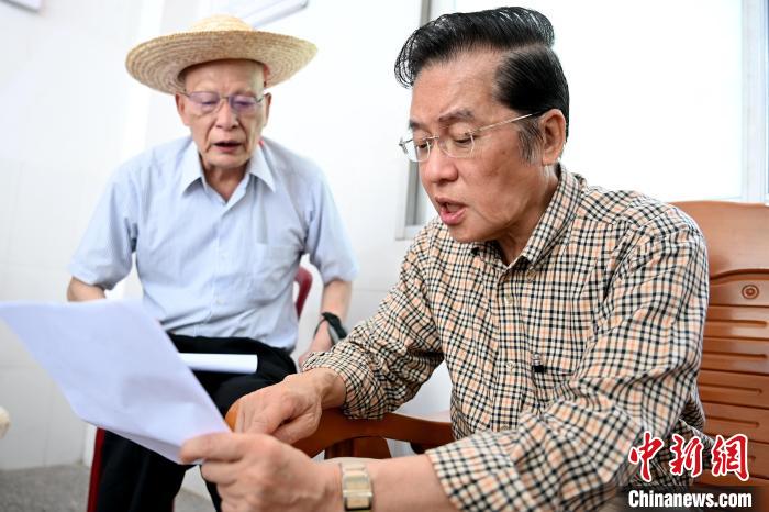 張榮恭(右)在詔安縣秀篆鎮北坑村與族親比對族譜。　張金川 攝