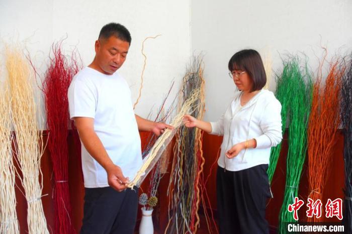 薛立憲(左)正在介紹龍柳工藝品。　李帥 　攝