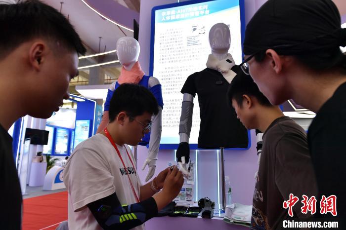 图为参观者在展会上体验具有人体健康监护预警功能的衣服。　张斌 摄