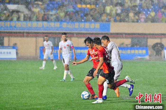 中国凭祥队球员(红)与越南谅山队球员在暴雨中激烈拼抢。　俞靖 摄