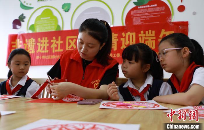 安徽省肥西县上派镇四十埠社区志愿者教小朋友剪纸。　陈家乐 摄