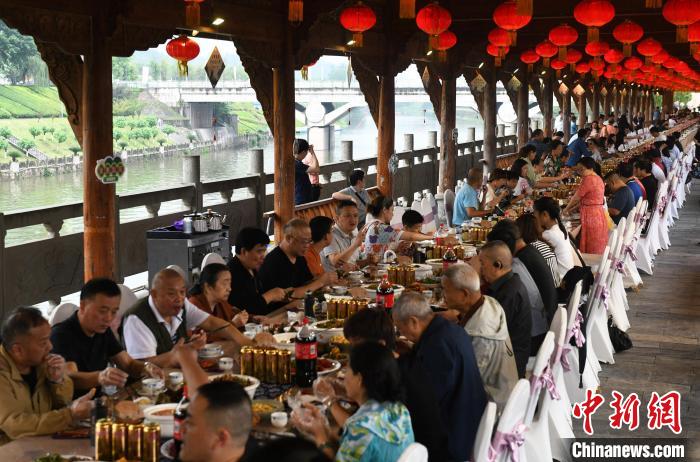 图为民众在廊桥上品尝长桌宴。　周毅 摄