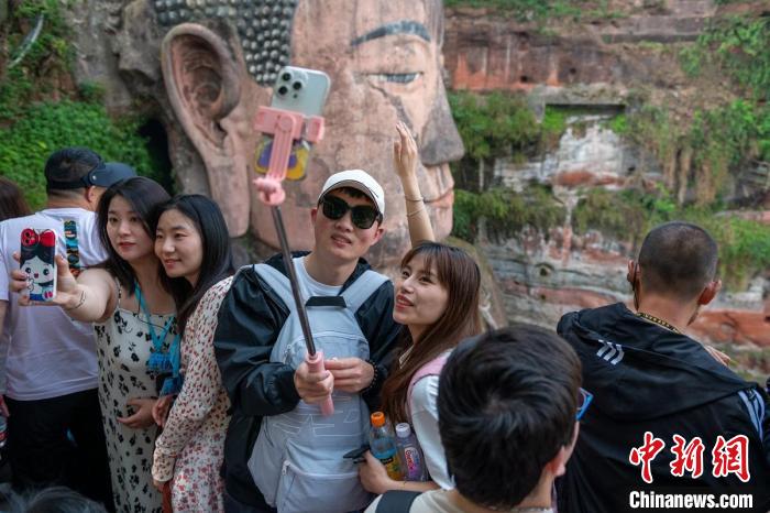 游客用手机与乐山大佛合影。(资料图) 刘忠俊 摄