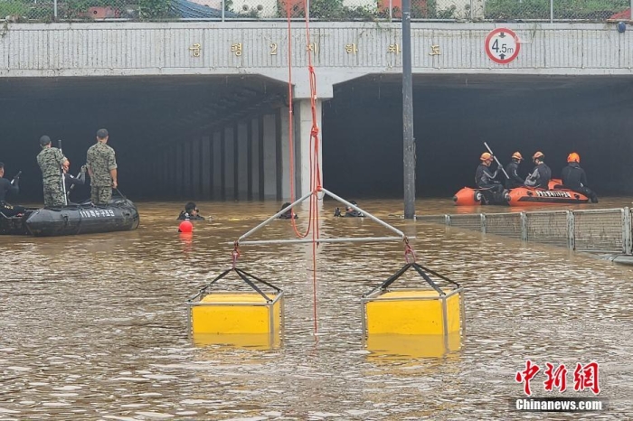 韩国救援人员沿着一条被洪水淹没的道路搜寻失踪人员，这条道路通往被洪水淹没的地下隧道。视觉中国