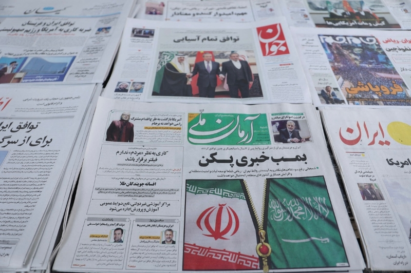 图为3月11日伊朗首都德黑兰市面有售的报纸，中共中央政治局委员、中央外办主任王毅、沙特国务大臣兼国家安全顾问艾班、伊朗最高国家安全委员会秘书沙姆哈尼的合照刊登在头版。（图源：路透社）