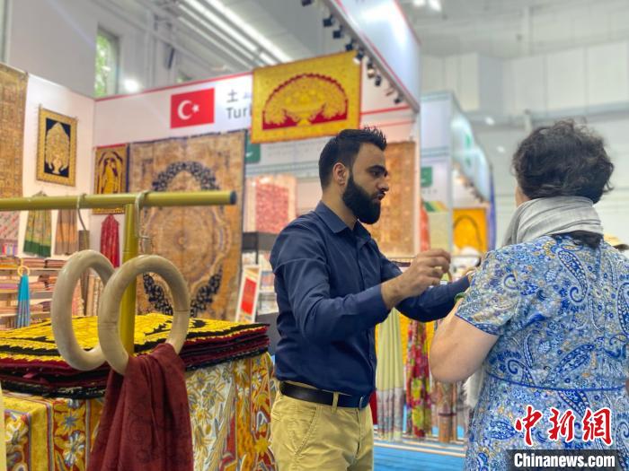 土耳其国家馆工作人员向游客展示当地文创产品。中新社记者张玮摄