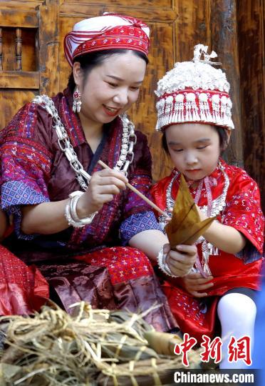 施秉县杨柳塘镇陆地坪苗寨一位苗族女子教孩子包粽粑。　奉力 摄