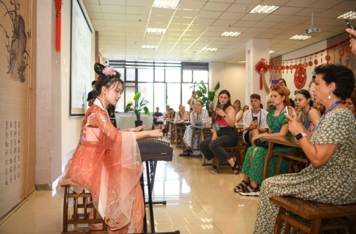 在新疆图书馆，乌鲁木齐古筝爱好者为国外歌舞团演员演奏《渔舟唱晚》(7月23日摄)。新华社记者 胡虎虎 摄