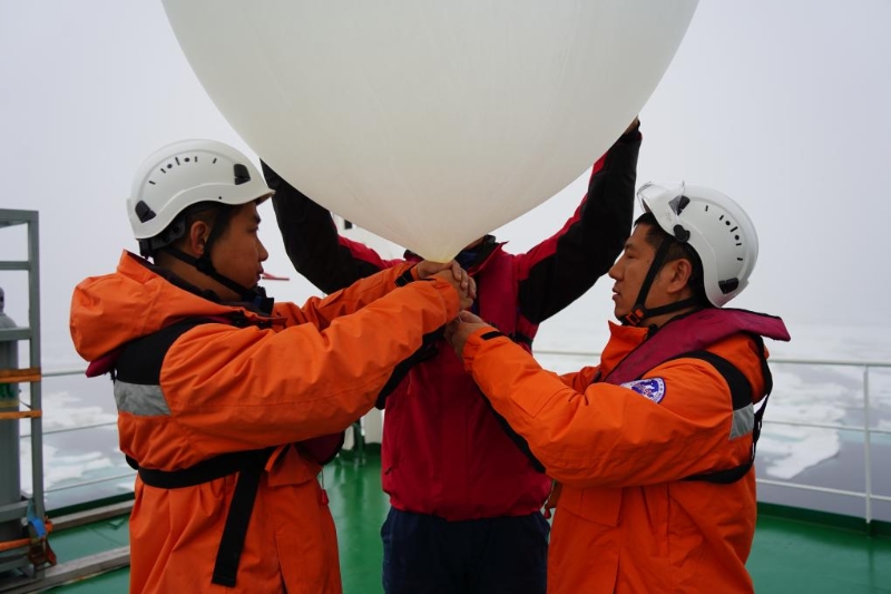 7月26日，中国第13次北冰洋科学考察队队员在执行气象探空气球布放作业。（图源：新华社）