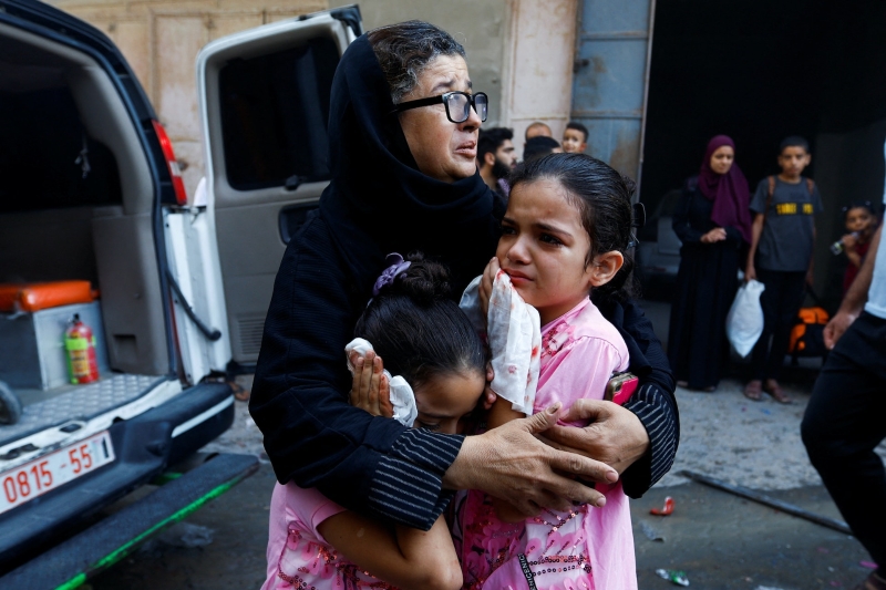 10月14日，在加沙地带，一名妇女忧心忡忡地抱着两名小女孩。（图源：路透社）