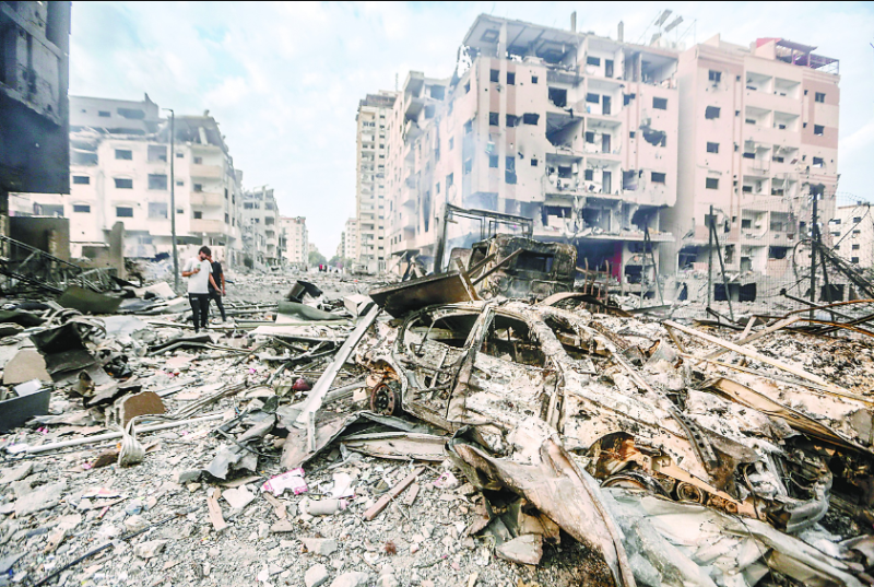 10月10日，在加沙城，人們走過被以色列空襲炸毀的建築廢墟。（視覺中國）.png