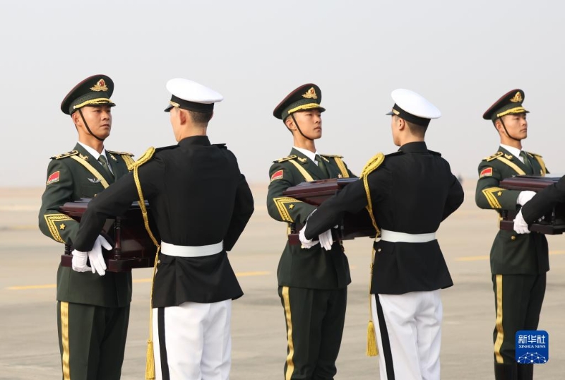 11月23日，在韩国仁川国际机场，中国人民解放军礼兵（左）从韩方接过中国人民志愿军烈士棺椁。（图源：新华社）