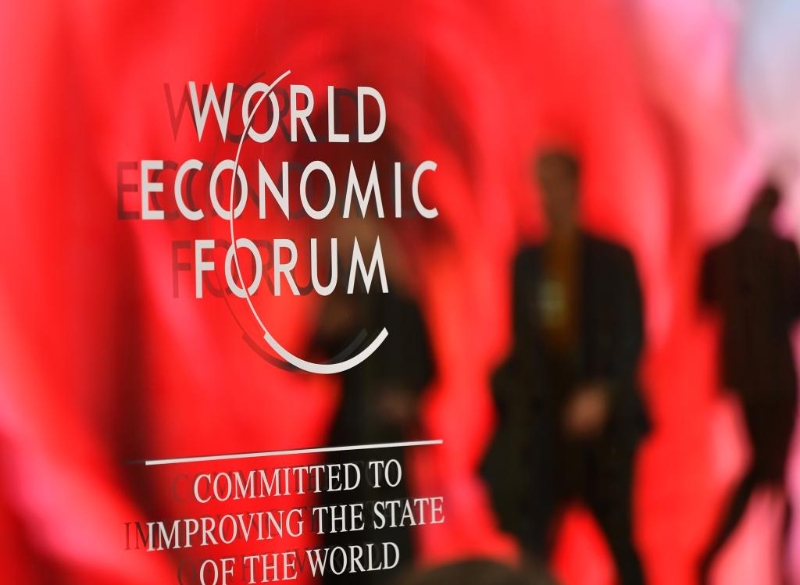 1月15日，在瑞士达沃斯，人们走过世界经济论坛标识。（图源：新华社）