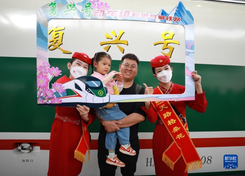 2023年7月1日，乘客与乘务人员在西宁至格尔木动车组首发列车前合影留念。（图源：新华社）
